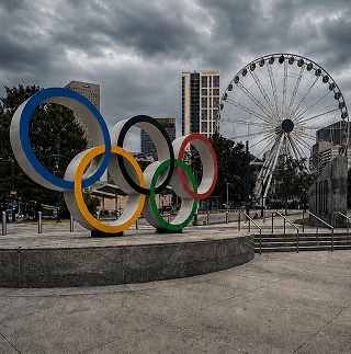 The Olympic rings in Centennial Olympic Park, Atlanta, under a heavy grey sky with the SkyView wheel behind.